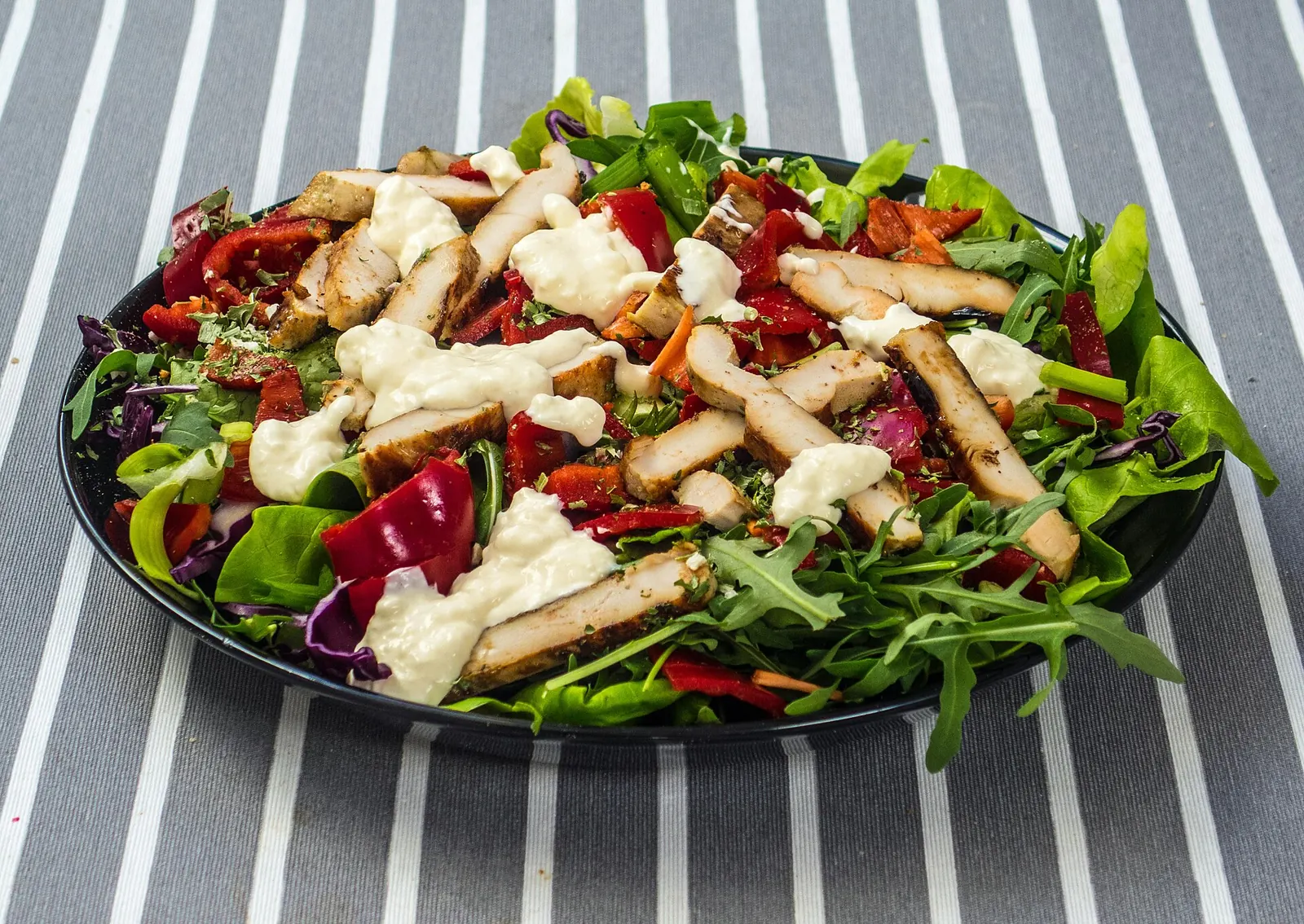 Salada com frango grelhado, rúcula, pimentão e molho branco.
